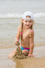  The three-year girl builds a sand castle on the beach