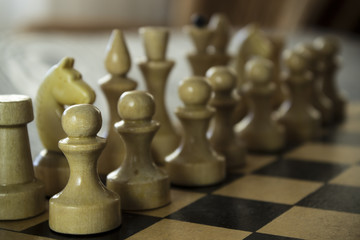 Wooden chess board with figures on the table. Focus on the nearest pawn