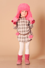 Cute baby girl 4-5 years old wearing trendy stylish winter clothes over beige background