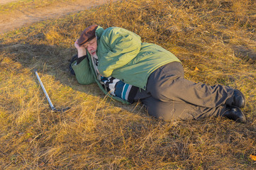 Naklejka na ściany i meble Senior hiker has short rest lying on the roadside at autumnal evening
