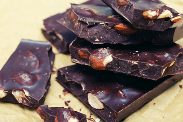 Dark chocolate with nuts on  on crumpled paper. Stack of assorted dark chocolate.