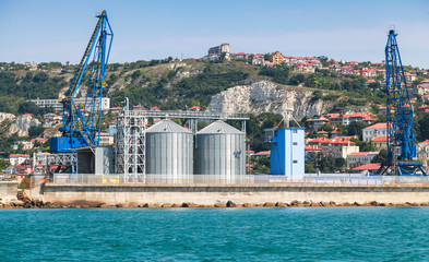 Cranes and tanks in Cargo terminal of Balchik port - obrazy, fototapety, plakaty