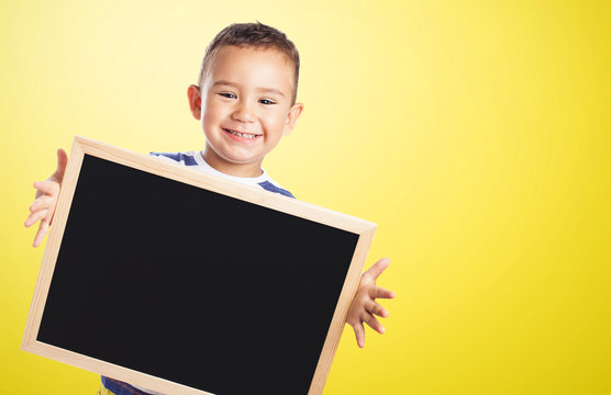 portrait of a cute kid holding a chalkboard