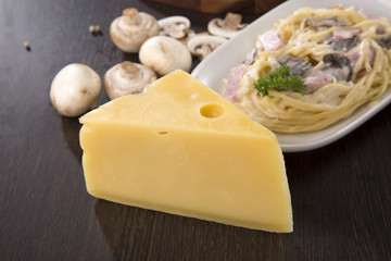 Cheese in triangle shape on table in front of spaghetti