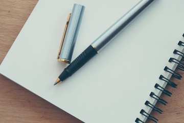 Naklejka premium paper notebook and pen on a table with filter effect retro vinta