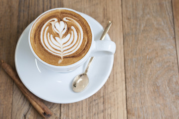 Cup of Latte art coffee with cinnamon on wooden table