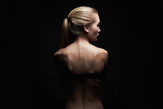 young woman with naked back over black background.sport body girl