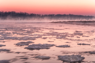 Freezing river covered in fog during dusk
