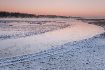 Freezing river covered in fog during dusk