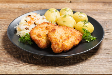 Fried pork chop in breadcrumbs, served with boiled potatoes and