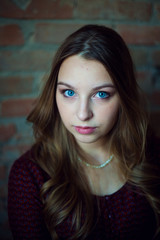 A young female  fashion model in dress against a brick wall background. She is looking at.