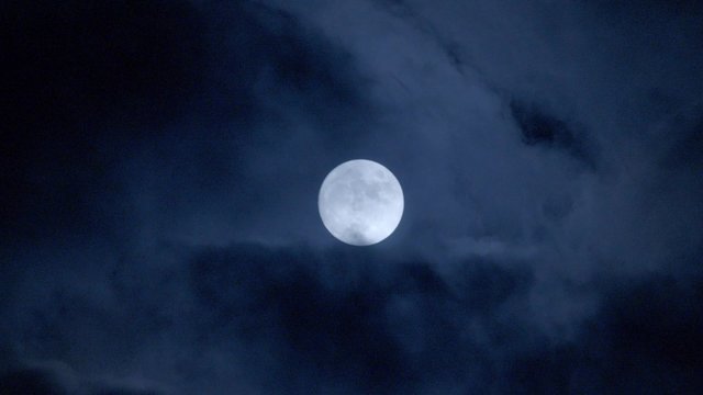 Full moon behind clouds at night. 4k