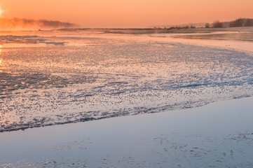 Sunrise over a freezing river covered in fog
