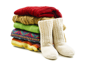 Wool socks and stack of various sweaters. Winter style. Isolated on white background 