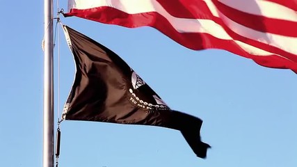 Tilting close-up shot of American and POW/MIA flags flying over Korean War Veterans Memorial