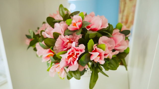 a bouquet of artificial flowers in a pot on the shelf