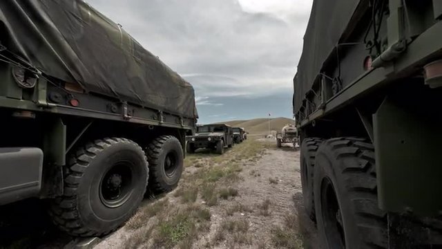 Time-lapse filmed between covered convoy trucks at a military training.