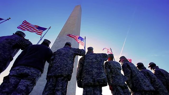 American soldiers saluting the American Flag at the Washington monument with sun flares, patriotic, static shot.