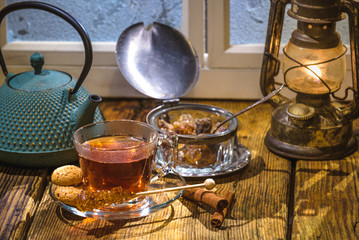 Glass cup of tea and sugar cane on a winter day outside the wind
