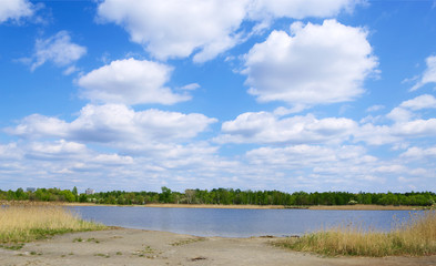 summer nature landscape with big cloudy blue sky above lake