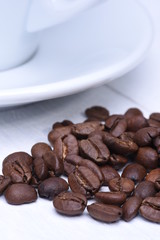 White cup of coffee and coffee beans on wooden background
