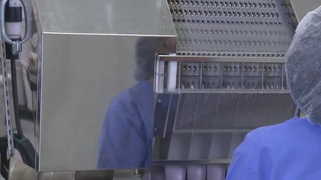 Tilting shot of a conveyor dropping pills in a container.