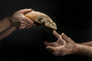 Mano di donna dona pagnotta di pane a un povero senzatetto. Concetto di povertà , emarginazione ,...