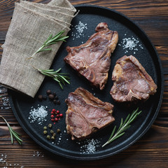 Frying pan with grilled T-bone lamb steaks, above view, close-up
