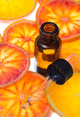 orange essential oil in amber bottle with blood orange slices  - 100271228