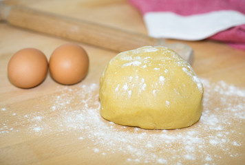 Short pastry dough and two eggs on wooden board.