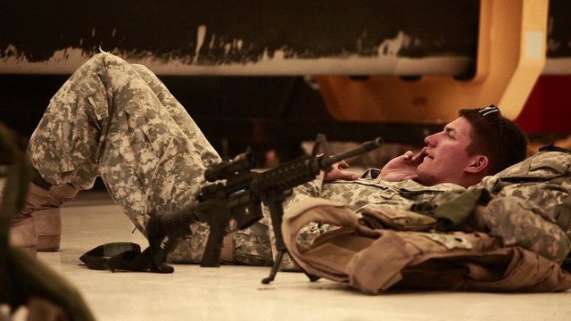 Soldier lying on the ground, talking on a cell phone.