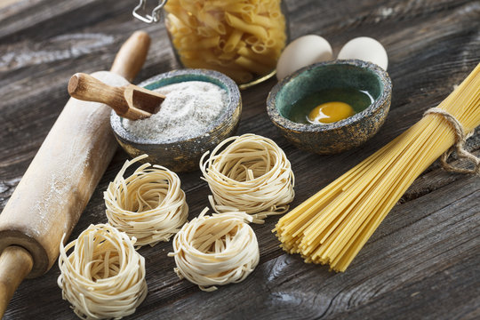 A set of raw pasta and addons on wooden table