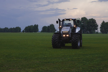 Fototapeta premium tractor with head lights in field at dusk