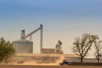 metal silo tank in countryside field tractor on foreground
