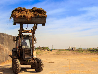 silo-loader tractor lifts ladle with silo in trench drives