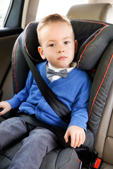 Portrait of little boy sitting in his car seat