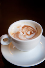 White cup of cappuccino stands on the table, selective focus 