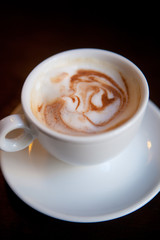 White cup of cappuccino stands on the table, selective focus 
