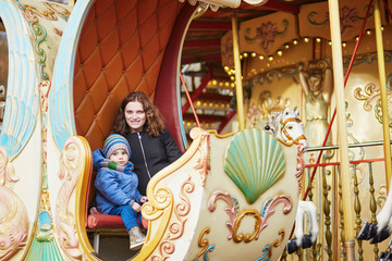 Obraz na płótnie Canvas Young mother with her adorable little son on Parisian merry-go-round