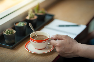writing on notebook with coffee cup