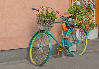 Fototapeta na wymiar Old bicycle with flowers and a basket by the wall. Decor