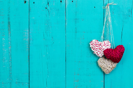 Red and white hearts hanging on teal blue wood background