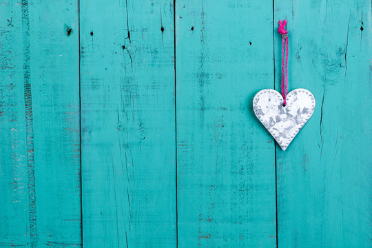 Tin heart hanging on rustic teal blue wood door