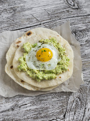 Homemade tortilla with mashed avocado and a fried quail egg. Delicious snack, healthy food