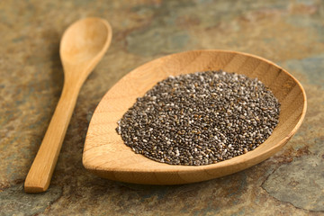 Chia seeds (lat. Salvia hispanica) on small bamboo plate, photographed with natural light. Chia seeds are considered a superfood (Selective Focus, Focus one third into the chia)