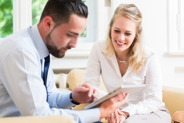 Fototapeta premium Geschäftsfrau und Mann bei Teammeeting schauen auf Präsentation am Tablet Computer