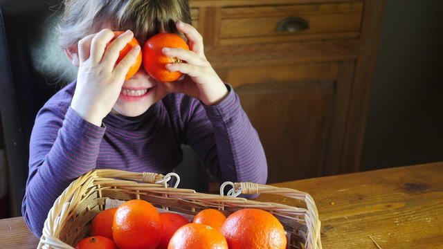 jolie fille joant avec des cl&eacute;mentines