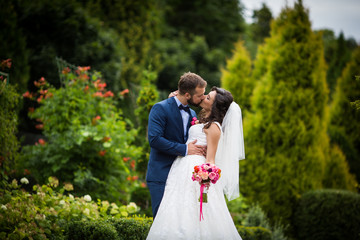 Handsome groom kissing beautiful bride with bouquet in romantic