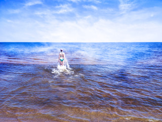 Beautiful girl walking on shining water of blue sea