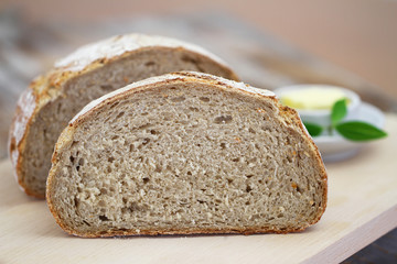 Rye bread cut in half on wooden board and butter
